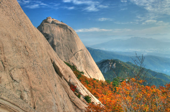 Aus einem herbstlich leuchtenden Wald gings hinauf auf den Gipfel. Im Hintergrund: Insubong.