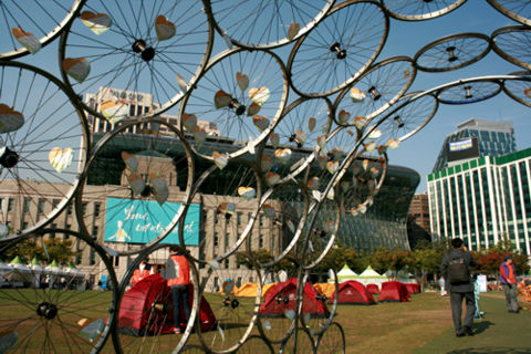 Fahrradtunnel und Zelte vor dem traditionelle und dahinter hochmodernen Rathaus.